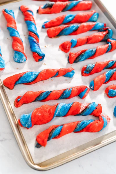 Stock image Rising patriotic cinnamon twists on the baking sheet lined with parchment paper.