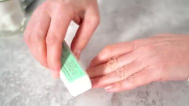 Zaman aşımı. Kadın manikürünü evde basit manikür aletleriyle bitiriyor. Çivi tampon bloğu ile tampon çiviler.