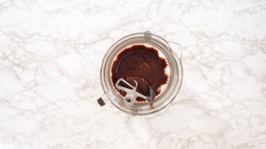 Düz yatıyordu. Adım adım. Elektrikli mutfak mikseriyle çikolatalı ganache çırpmak..