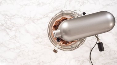 Düz yatıyordu. Adım adım. Elektrikli mutfak mikseriyle çikolatalı ganache çırpmak..