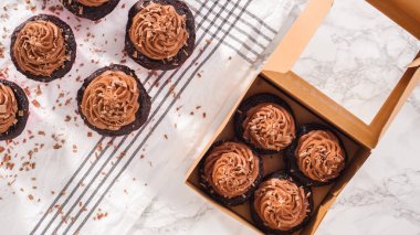 Düz yatıyordu. Adım adım. Çikolatalı kapkekleri çikolatalı ganache ile paketleyip kek kutusuna koymak..
