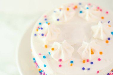 Beyaz kek tabağına funfetti serpiştirilmiş küçük beyaz doğum günü pastası.