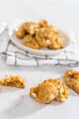 Beyaz bir tabakta taze pişmiş beyaz çikolatalı macadamia fındığı..