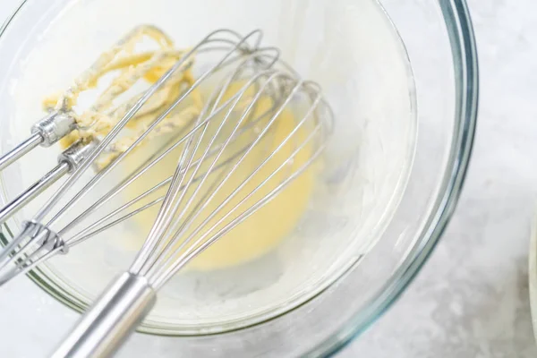 Dirty whisks in a glass mixing bowl after baking a cake.