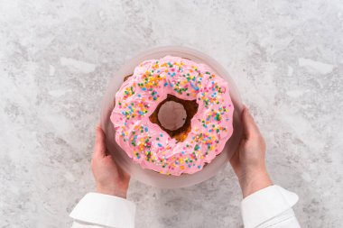 Düz yatıyordu. Pembe vanilyalı krema kaplı ve gökkuşağı parçacıklarıyla süslenmiş Funfettti demetli kek..