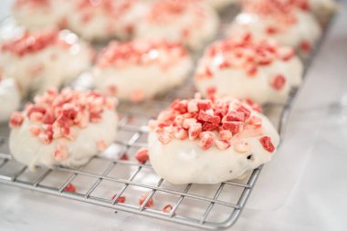 Naneli beyaz çikolatalı kurabiyeler hazırlamak için eritilmiş beyaz çikolataya çikolatalı kurabiyeler batırmak..