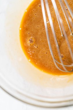 Mixing ingredients with a hand mixer in a small mixing bowl to make the caramel filling for bundt cake.