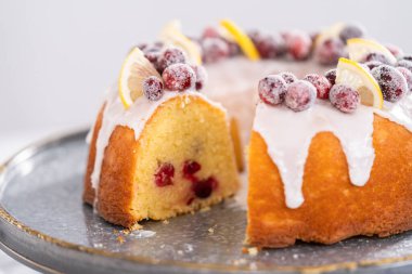 Dilimlenmiş limonlu kek. Şeker kızılcıkları ve limon dilimleri ile süslenmiş..