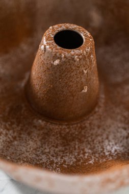 Greasing metal bundt cake pan with vegetable shortening and cocoa powder to bake gingerbread bundt cake with caramel filling.