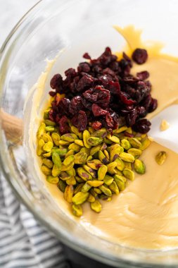 Eriyen beyaz çikolata parçacıkları ve diğer malzemeler kaynamış suyun üzerinde karışıp kızılcık fıstıklı şekerleme hazırlıyor..