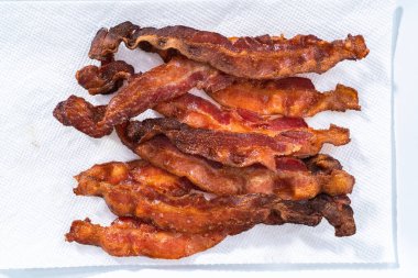 Beyaz tepside pişmiş pastırma şeritleri ve kağıt havlu..