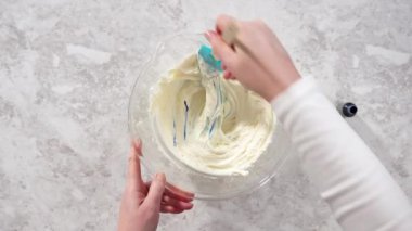 Düz yatıyordu. Tereyağlı kremaya mavi gıda boyası karıştırıyorum..