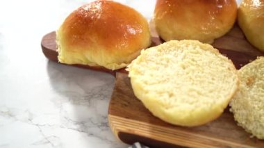 Adım adım. Odun kesme tahtasının üzerinde taze pişmiş çörekleri dilimliyorum..