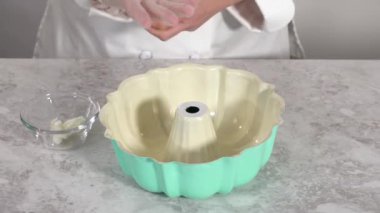 Time lapse. Greasing bundt cake pan with vegetable shortening and flour to bake funfettti bundt cake.