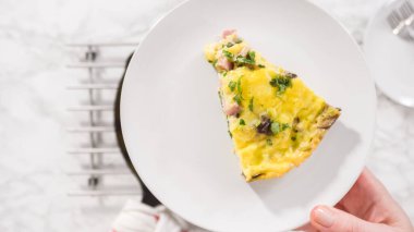 Düz yatıyordu. Adım adım. Fırından yeni çıkmış ıspanak ve jambonlu frittata dilimliyorum..