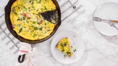 Düz yatıyordu. Adım adım. Fırından yeni çıkmış ıspanak ve jambonlu frittata dilimliyorum..