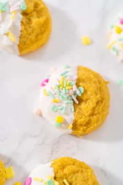 Beyaz çikolatalı limonlu kurabiye. Limonlu kurabiyeleri erimiş beyaz çikolataya batırıp Paskalya şekerleriyle süslemek..