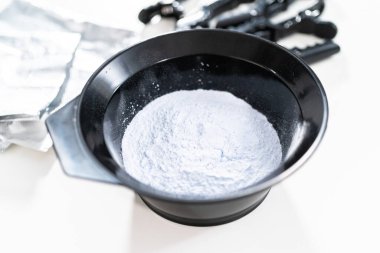 Siyah plastik bir kasede beyaz arka planda saç boyası tozu..