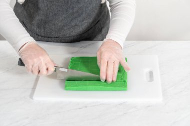 Büyük bir mutfak bıçağıyla yeşil şekerlemeyi beyaz bir kesme tahtasında kare parçalara ayırmak..