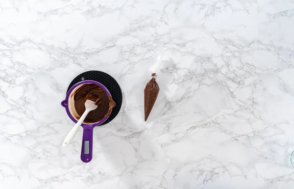 平置きだ チョコレートチップをキャンディーポットで溶かし パンダの形をしたショートブレッドクッキー用にチョコレートアイシングを作ります — ストック写真