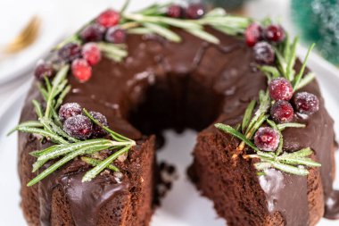 Dilimlenmiş çikolatalı kek taze kızılcıklarla süslenmiş çikolata kremalı ve beyaz şekerle kaplanmış biberiye..