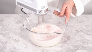 Adım adım. Vanilyalı kremanın içine pembe gıda boyası karıştırarak funfettti desenli pastayı süslemek için..