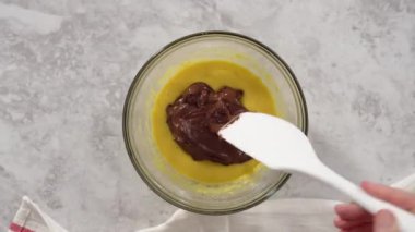 Time lapse. Flat lay. Step by step. Mixing ingredients in a glass mixing bowl to prepare chocolate mug cakes.