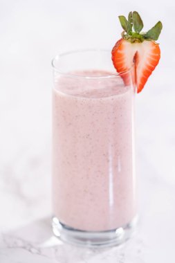 Taze taze çilek ve kağıt kamışla süslenmiş sağlıklı bir kahvaltı muzlu smoothie..