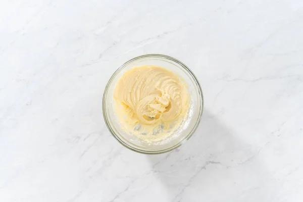 stock image Flat lay. Mixing ingredients in a large glass mixing bowl to make the cream cheese filling for bundt cake.