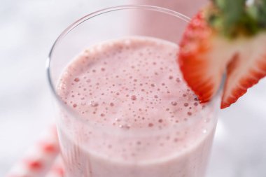 Taze taze çilek ve kağıt kamışla süslenmiş sağlıklı bir kahvaltı muzlu smoothie..