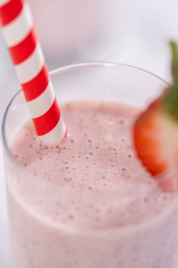 Taze taze çilek ve kağıt kamışla süslenmiş sağlıklı bir kahvaltı muzlu smoothie..