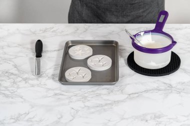 Filling silicone mold with white melted chocolate to make chocolate chocolate stars for American flag mini cupcakes.