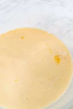 Amerikan bayrağı mini kekleri yapmak için ıslak malzemeleri büyük bir bardakta karıştırıyorum..