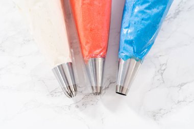 Amerikan bayrağı mini keklerini süslemek için metal uçlu boru torbalarının içinde tereyağlı krema..