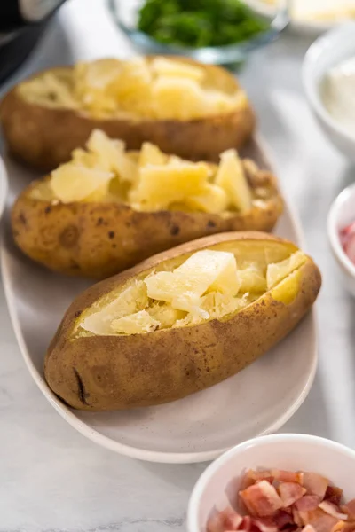 Pressure Cooker Baked Potatoes. Sliced cooked whole potatoes on a white plate to make baked potatoes.