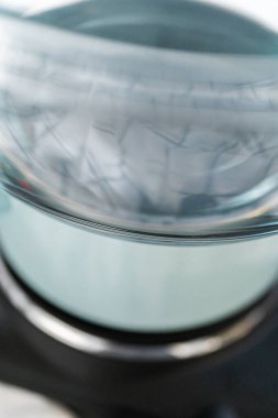 Eriyen beyaz çikolata parçaları ve diğer malzemeler kaynamış suyun üzerine karıştırıp çubuk şekerleme hazırlıyor..