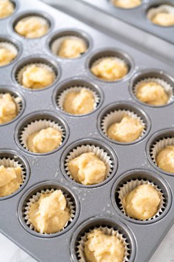 Scooping cupcake batter with dough scoop into a baking pan with liners to bake American flag mini cupcakes.