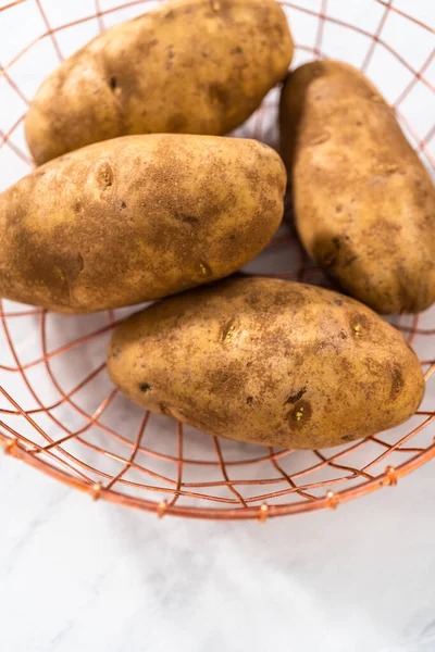 Pressure Cooker Baked Potatoes. Raw potatoes in a wire basket on the kitchen counter.