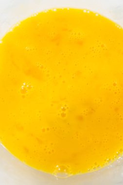 Büyük bir bardakta ıslak malzemeler karıştırarak kırmızı kadife kekler ve beyaz çikolatalı ganache kreması pişiriyorum..