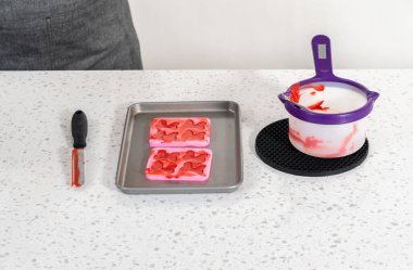 Flat lay. Filling bow silicone chocolate mold with melted chocolate to make a chocolate pretzel Christmas wreath.