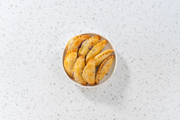 平置きだ 焼き立ての甘いエンパナーダとブルーベリーがキッチンカウンターに — ストック写真