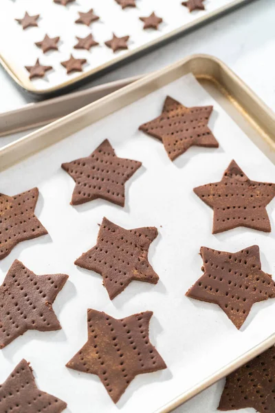 stock image Unbaked star-shaped chocolate graham crackers on the baking sheet lined with parchment paper.