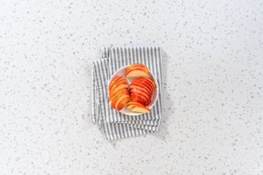 Düz yatıyordu. İnce dilimlenmiş kırmızı elmalar beyaz bir tabakta.