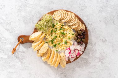 Düz yatıyordu. Sebzeli tereyağı tahtası ve tahta kesme tahtasında ekmek..