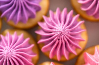 Beyaz pasta standında pembe tereyağlı taze pişmiş mini vanilyalı kekler..