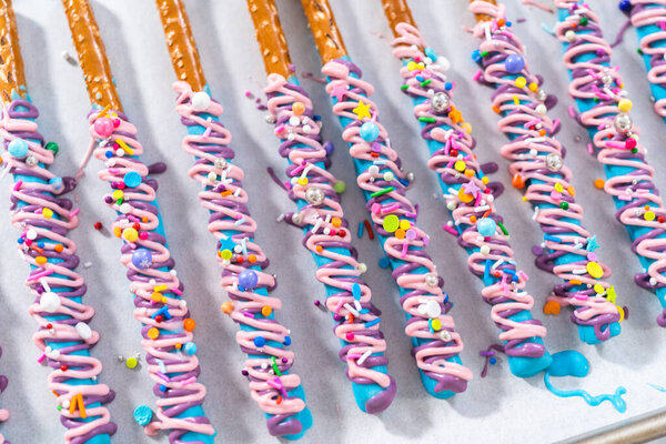 Mermaid chocolate pretzel rods drizzled with pink and purple chocolate and covered with sprinkles.