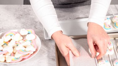 Adım adım. Taze pişmiş tek boynuzlu at kurabiyelerini fırından alıp beyaz servis tabağına koyuyorlar..