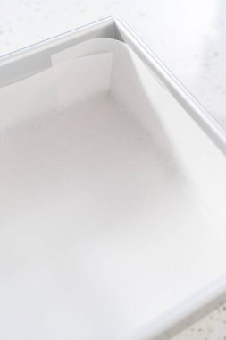 Çikolatalı şam fıstıklı şekerleme hazırlamak için parşömen kağıdıyla kare çizgili cheesecake tavası..