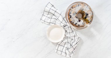 Düz yatıyordu. Taze pişmiş limonlu yaban mersinli kek dilimliyorum. Pudra şekerli..