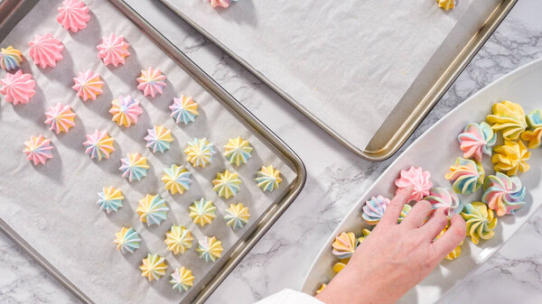 Step by step. Flat lay. Freshly baked unicorn meringue cookies on a baking sheet with a parchment paper.
